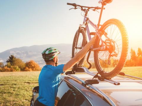 Mann mit Fahrrad auf Dach eines Autos